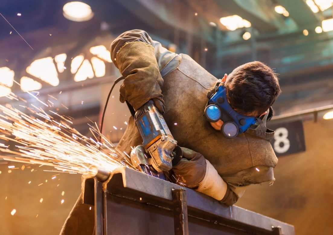 A man wearing protective gear while using an angle grinder.