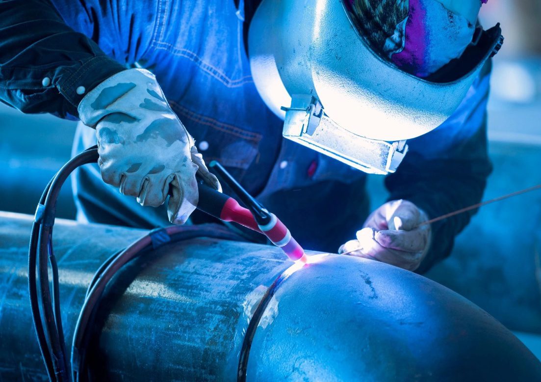 A person welding in the dark with blue light.