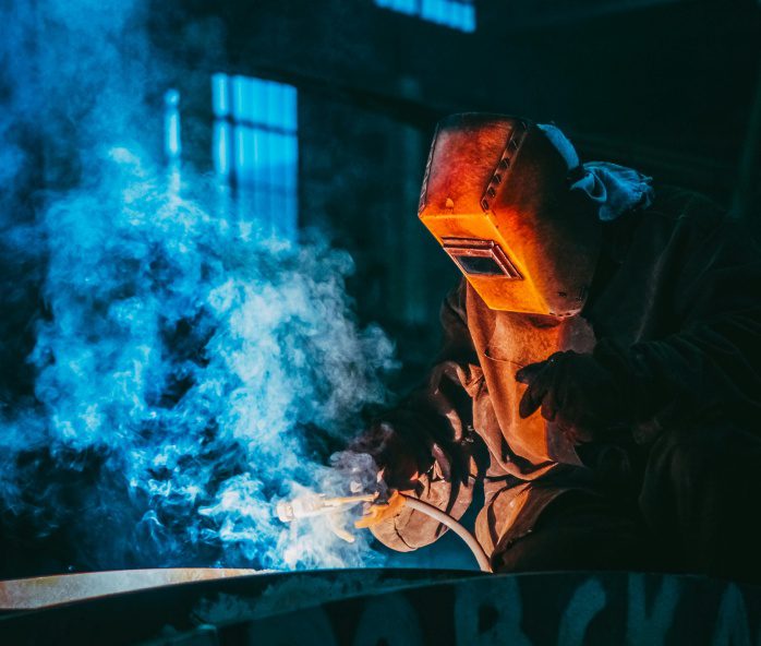 A person welding with blue smoke coming out of the back.